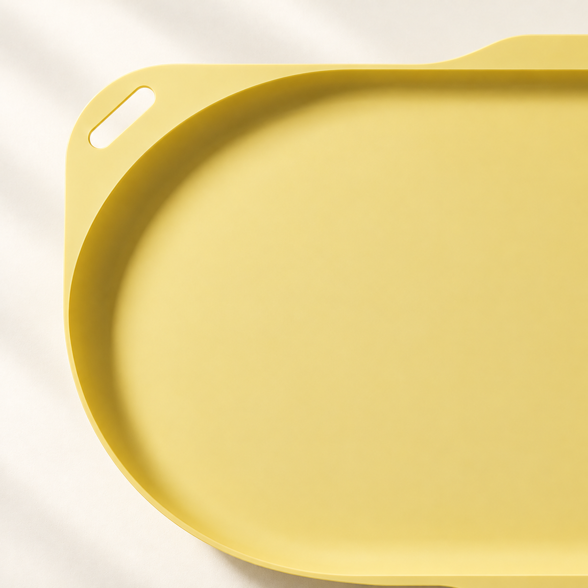 Close-up of the yellow feeding tray’s raised rim, smooth surface and handle opening.