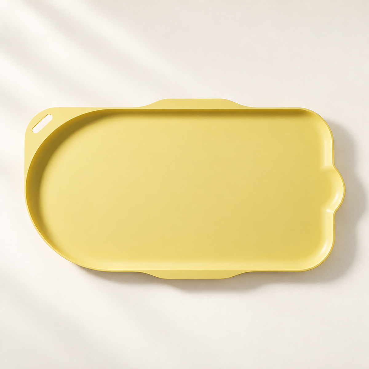 Yellow cat-shaped feeding tray viewed from above on a warm neutral surface.