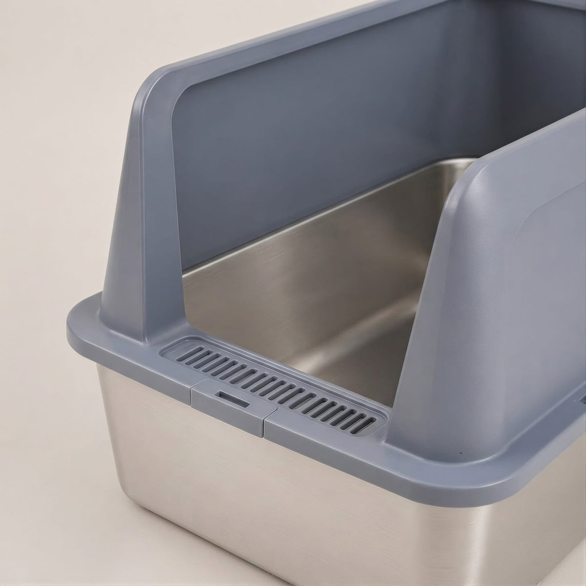 Close-up of the slotted entry and brushed stainless steel base of the grey cat litter box