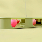 Close-up of colourful balls visible through side openings in the green cat activity toy.