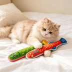 Cream-coloured cat lying on a bed with green and orange-red plush fish kicker toys under its paws.