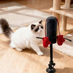 Fluffy white and brown cat beside a black boxing teaser toy with red hanging gloves and a suction cup base.
