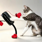Grey and white cat batting a tilted black punching-bag toy with red gloves and a red suction base.